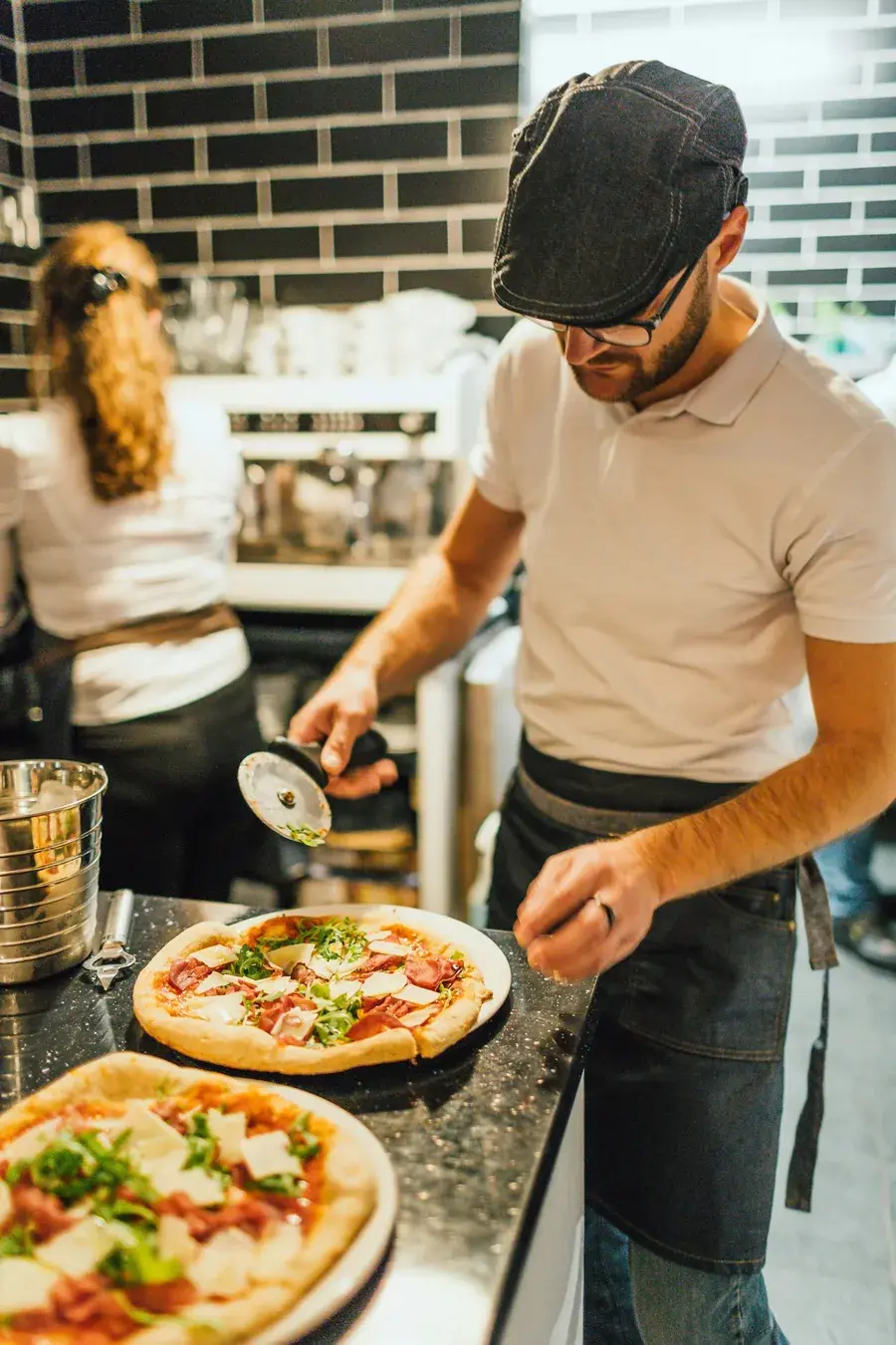Kuba Leśniak, pizzaiolo pizzerii Rumiana, kroi świeżo upieczoną pizzę